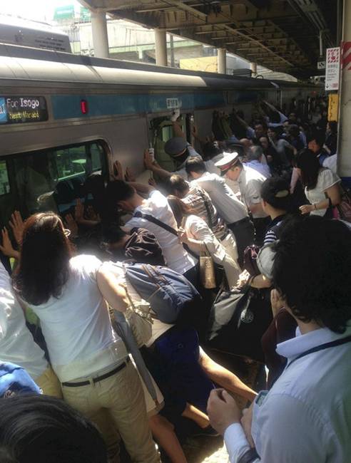 Japán utasok, akik segítenek megbillenteni a vonatot, hogy kiszabadítsák egy nő vonat-peron közé ragadt lábát.