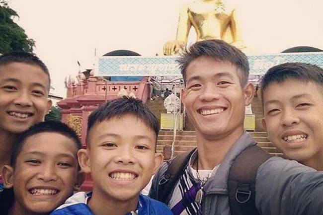 Az elárasztott Tham Luang-barlangrendszerből kiszabadított thaiföldi gyermekek, akik épp az edzőjükkel szelfiznek, aki segített nekik életben maradni.