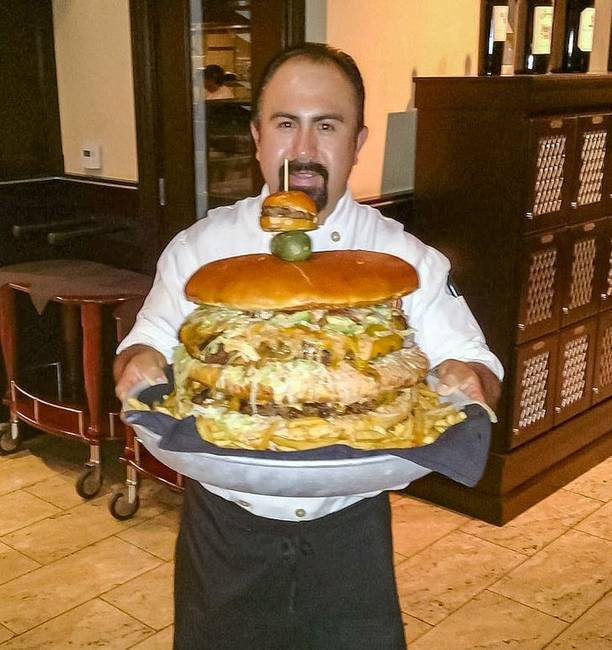 Egy óriás hamburger, a tetején egy normál méretű hamburgerrel, mint díszítés.