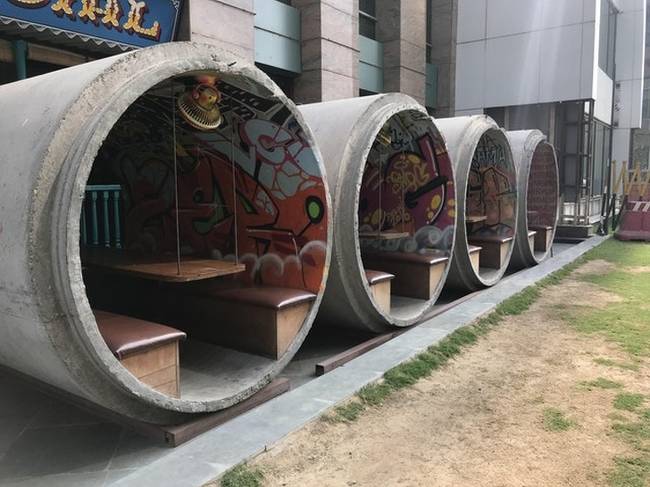 Egy étterem, ahol csatornaépítéshez használt betonelemeket használnak, hogy fedett teraszt biztosítsanak a vendégeknek.