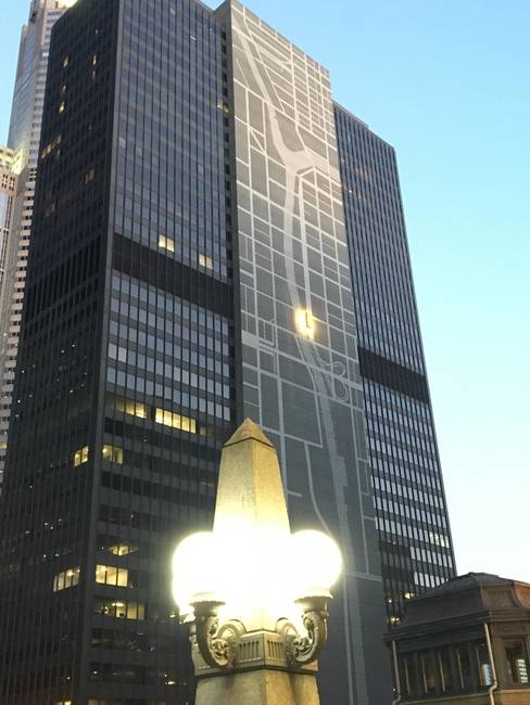 Egy chicagói épület, aminek az oldalán egy várostérkép látható, melyen az is fel van tüntetve, hogy hol állunk pontosan.
