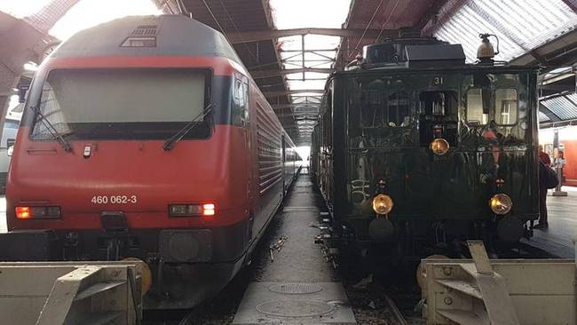 Új és régi vonat találkozása egy állomáson.