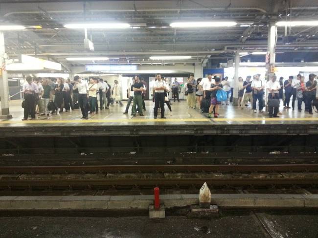 A japán emberek libasorba rendeződve várják a metrót.