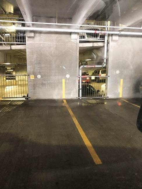 Egy parkolóház, ahol az útburkolati jelek a falon is folytatódnak, hogy így könnyítsék meg a parkolást.