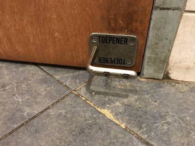 Egy nyilvános mosdó ajtaja, ami lábban is nyitható, így nem kell megfognunk a baktériumoktól hemzsegő kilincset.