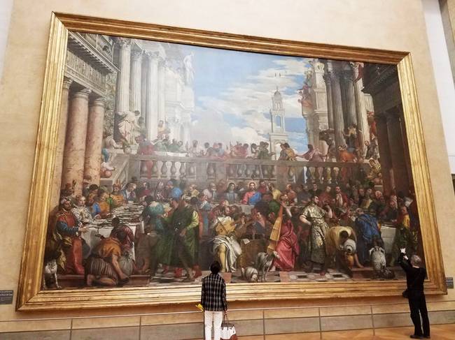 A kép, ami közvetlenül a Mona Lisa-val szemben található a párizsi Louvre-ban.