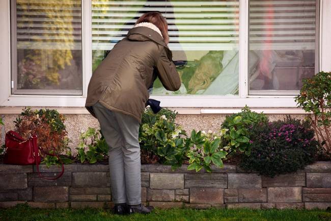Laurie Spencer az anyjával, Judy Shape-el beszélget az ablakon keresztül egy egészségügyi központban.